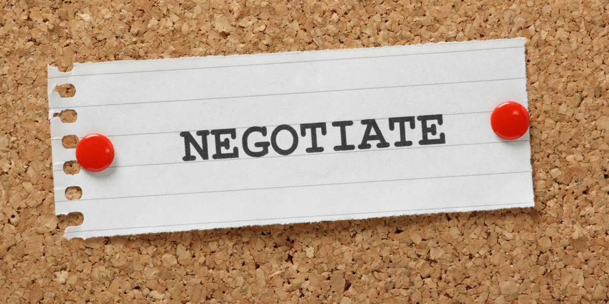 Torn piece of paper with word negotiate pinned to corkboard