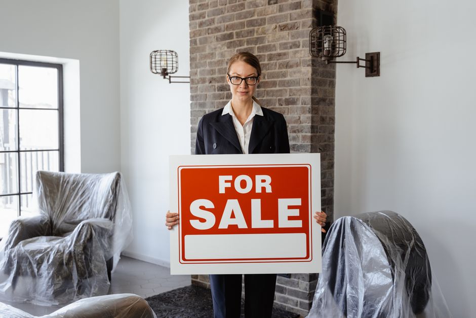 A sleek, modern 'For Sale' sign in the manicured front yard of a beautiful home, representing the process of listing a property.