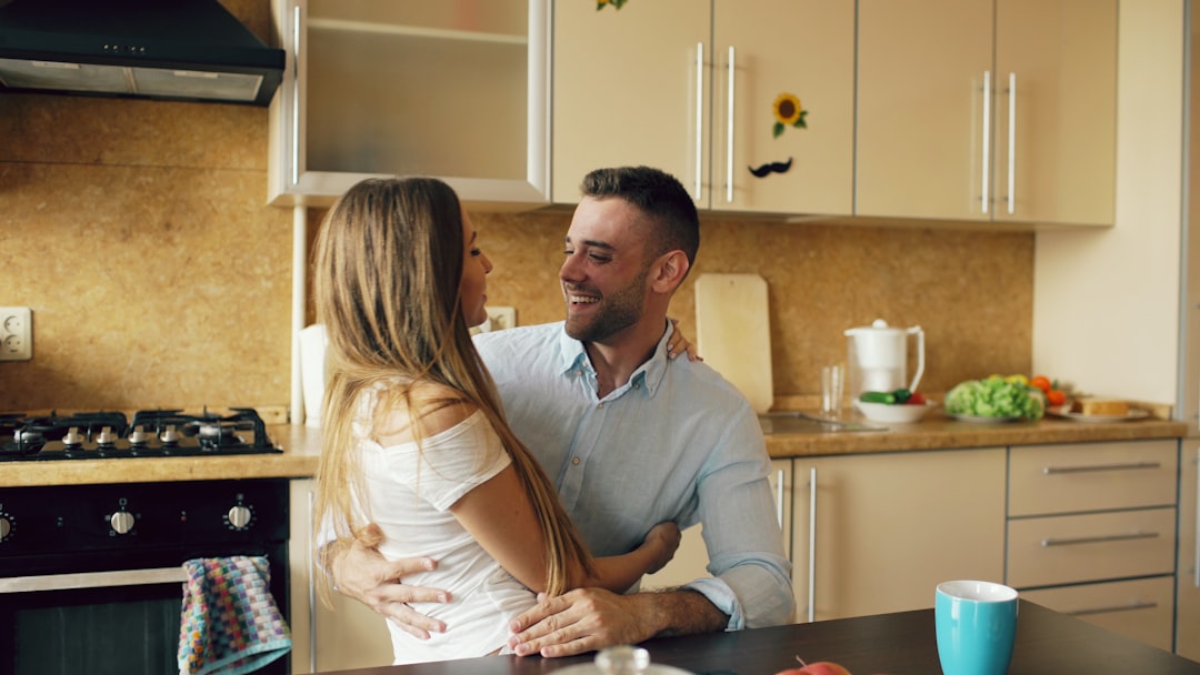 A smiling couple sits at a clean, modern kitchen island, looking over a document together, representing the peace of mind after a home inspection.